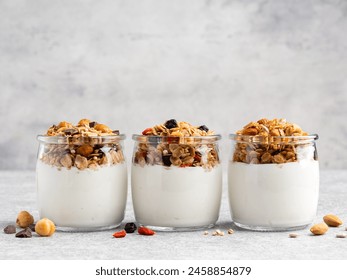 Set of granola with yogurt jars. Healthy homemade muesli made of rolled oats, hazelnut, almond, goji berries, chopped dark chocolate and dried blueberry served with greek yoghurt. Close up, copy space - Powered by Shutterstock