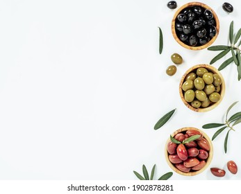 Set of green olives, black olives and red kalmata olives on white background,copy space. Top view of different olives types in bowls and leaves and branches isolated on white. Beautiful olive flat lay Foto Stock