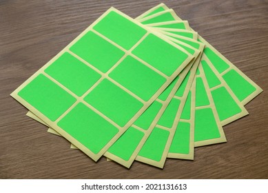 A set of green rectangular paper sticker label on wooden background.