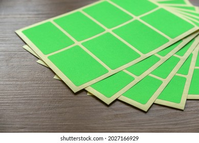 A set of green rectangular paper sticker label on wooden background.