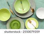 Set of green tableware and cutlery on turquoise grunge background