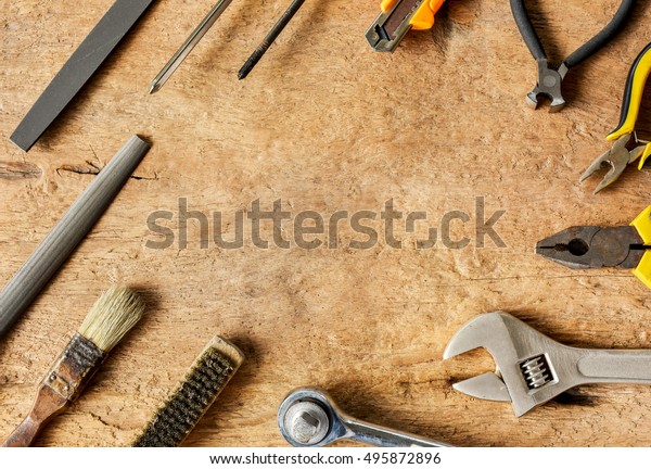 Set of hand tools in workshop on wood\
background. Hand tools for general work and home maintenance array\
on wood background.
