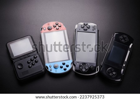 Set of handheld portable video game consoles with switch detachable controllers on both sides isolated on black background, Hybrid wireless gadget