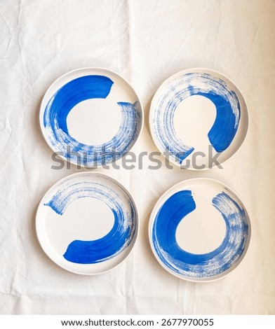  A set of handmade ceramic deep plates with a bowl like edge decorated with a bold cobalt oxide brush stroke