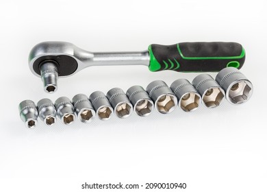 Set of hexagonal sockets different sizes with metric marking laid out in a row on a background of the ratchet wrench on a light surface
