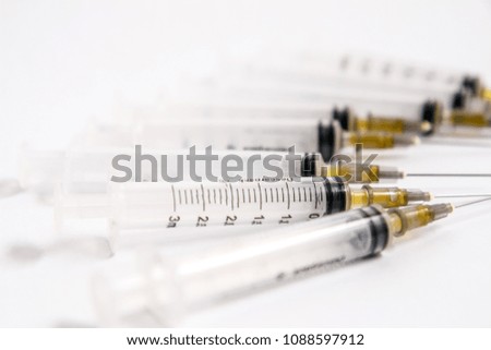 set of hypodermic plastic syringes on white background with exposed needles.