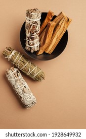 Set of incense for fumigation. White sage, cedar, yerba santa, and Palo Santo sticks tied in bunch in metal bowl. View from above. Organic holy tree incense from Latin America. Close-up color photo.