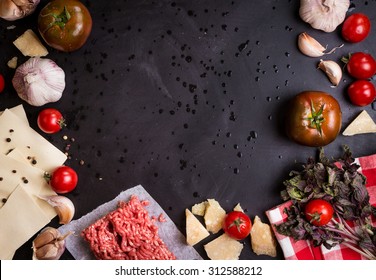 Set Of Ingredients For Italian Lasagna. Black Food Background With Free Space For Text. Pasta, Tomatoes, Fresh Ground Meat, Parmesan, Mozzarella, Basil, Garlic On A Rustic Chalkboard. Overhead