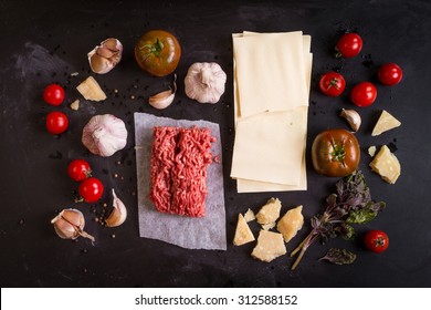 Set Of Ingredients For Italian Lasagna. Pasta, Tomatoes, Fresh Ground Meat, Parmesan, Mozzarella, Basil, Garlic On A Rustic Chalkboard. Overhead