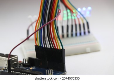 Set of jumper wires connected to a microcontroller board that completes the circuit with Breadboard and LED showing prototyping electronic projects concept