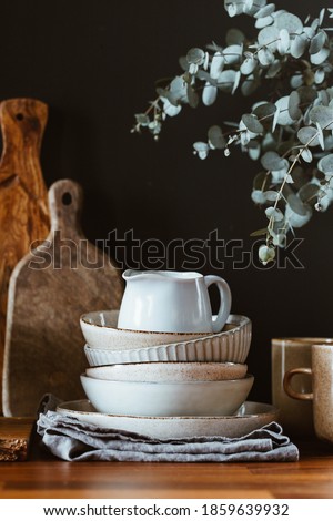 Set of kitchen ceramic tableware and wooden cutting boards on a table. Eco style home still life.