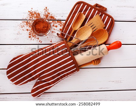 Set of kitchen utensils with cocoa in mitten on wooden background