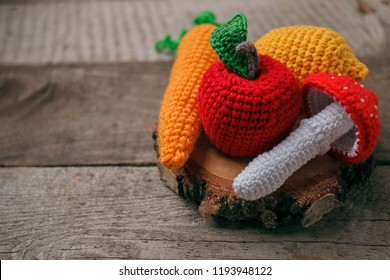 set of knitted toys lemon, carrot, apple, amanita on wooden background. Earlier tactile development of children, craft toys, vegetarian menu concept, copy space