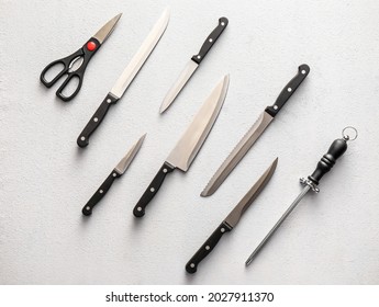 Set of knives with sharpener and scissors on light background