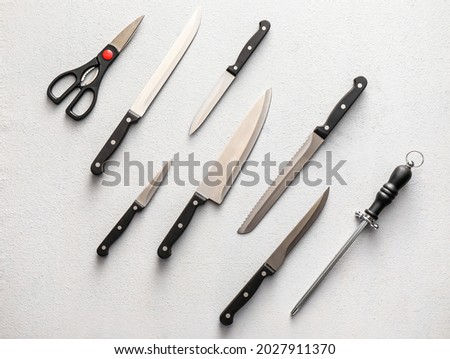 Set of knives with sharpener and scissors on light background