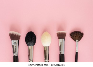 Set of large cosmetic brushes on pink background.