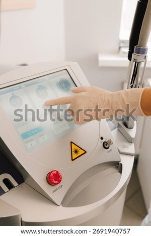 Set laser parameters through a touchscreen interface, preparing equipment for dermatological use. Healthcare technician programs laser equipment via touchscreen, adjusting pulse rate and wavelength