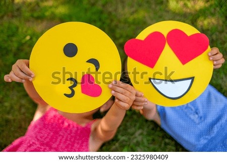 A set of love emoticons in close-up. Girls demonstrate cardboard smile faces with different emotional moods