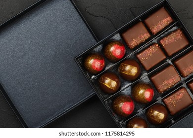 Set of luxury handmade bonbons in box on black background. Exclusive handcrafted chocolate candy. Product concept for chocolatier. Copy space