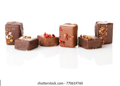 Set of luxury handmade bonbons decorated with szechuan pepper and Maldon sea salt on white background. Exclusive handcrafted chocolate candies. Product concept for chocolatier