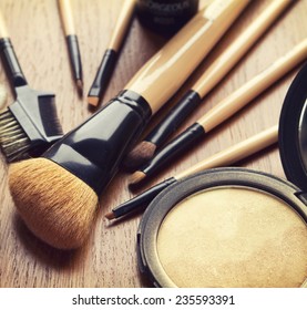 Set of makeup brushes and gold bronzer highlighter powder
