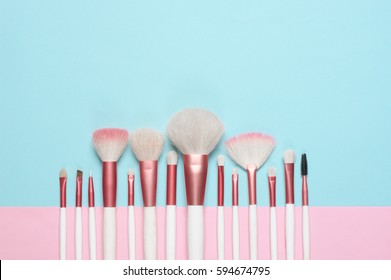 Set of makeup brushes on pink and aqua colored composed background. Top view point, flat lay.