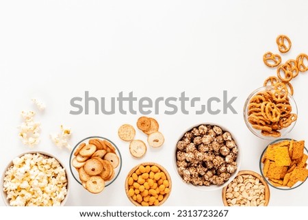 Set of many salty snacks in bowls - pretzels nuts chips top view.