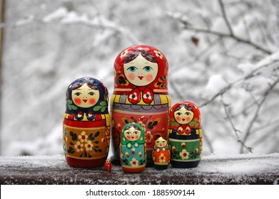 Set of Matryoshka Russian dolls in traditional bright colored clothes standing in the winter background