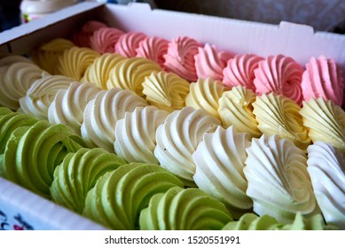 Set of meringue cakes in four colors: white, yellow, green, pink