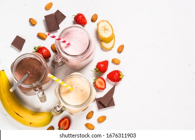 Set of milkshake or smoothie in mason jars. Banana, chocolate and strawberry milkshakes with nuts. Summer dessert. Healthy food. Top view.