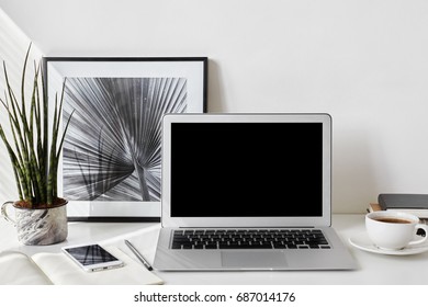 Set Of Modern Electronic Devices On White Office Desk. Freelancer's Desktop With Blank Screen Laptop, Stationery Items, Framed Picture, Mobile Phone, Decorative Plant And Cup Of Coffee. Mock Up