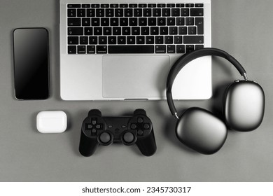 Set of modern gadgets on a beautiful dark or gray background with headphones, laptop, phone, joystick and camera
					