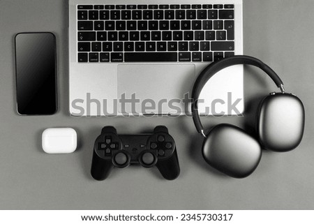 Set of modern gadgets on a beautiful dark or gray background with headphones, laptop, phone, joystick and camera
