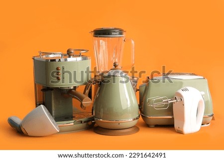 Set of modern household appliances on orange background