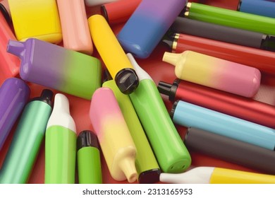 Set of multicolor disposable electronic cigarettes on a red background. The concept of modern smoking, vaping and nicotine.