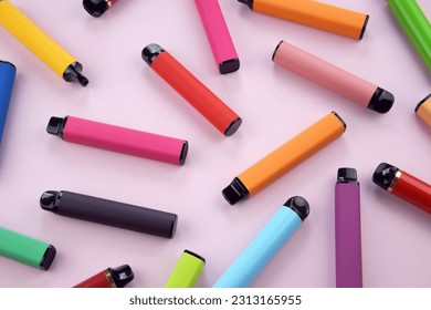 Set of multicolor disposable electronic cigarettes on a pink background. The concept of modern smoking, vaping and nicotine.