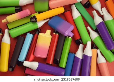 Set of multicolor disposable electronic cigarettes on a red background. The concept of modern smoking, vaping and nicotine.