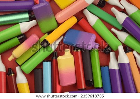 Set of multicolor disposable electronic cigarettes on a red background.