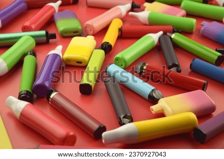 Set of multicolor disposable electronic cigarettes on a red background. The concept of modern smoking, vaping and nicotine.