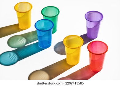 Set Of Multi-colored Plastic Cups On A White Background. Long Shadows, Studio Shot.