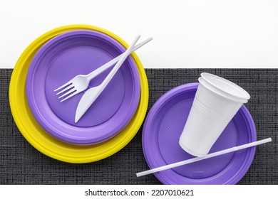 A Set Of Multi-colored Plastic Utensils On A Black And White Background, Top View.