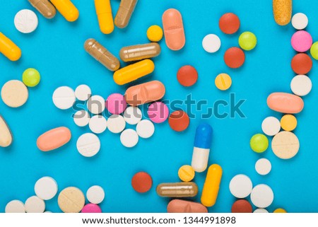 set of multi-colored tablets and capsules on a blue background - Image