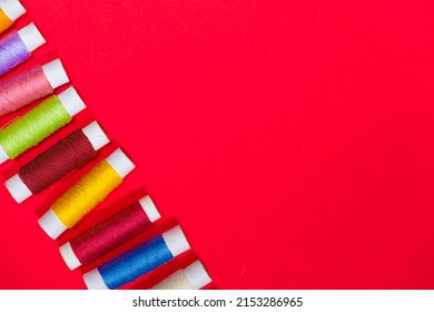 A Set Of Multi-colored Threads For Sewing With An Empty Space For Text On A Red Background, Top View. Tailoring And Needlework Equipment, Tailor Banner.
