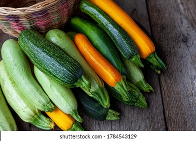 A set of multi-colored zucchini yellow, green, white, orange on the table close-up. Food background. Fresh harvested courgette, cropped summer squash. Picked green courgettes. Still life in kitchen.