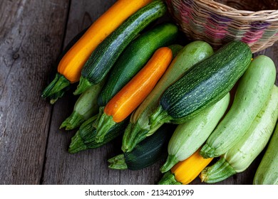 A set of multi-colored zucchini yellow, green, white, orange on the table close-up. Food background. Fresh harvested courgette, cropped summer squash. Picked green courgettes. Still life in kitchen.