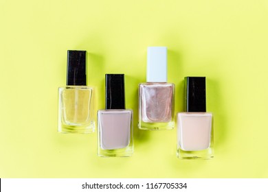 set for nail polish on yellow table background top view mock up.collection of various nail polish bottles.Nude collors. Nails care. Manicure, pedicure beauty salon