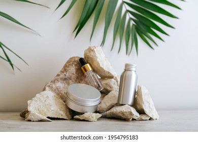 Set Natural Unisex Beauty Cosmetic Skincare Products For Man In Aluminum Jars Bottle With Palm Leaf On Stone Pedestal, Balancing Rock Pile On Gray Background. Kit Hair Body Skin Care Cosmetics