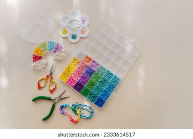 Set of for needlework and beading with tools for making jewelry. Handmade bracelets and different beads for children's crafts in boxes. DIY art activity for kids. Motor skills, creativity and hobby.