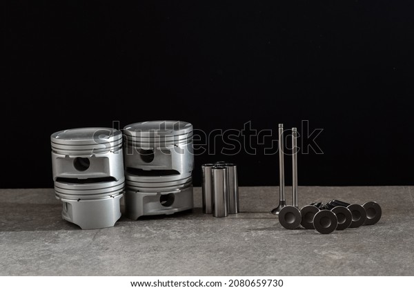 Set of new car pistons and\
valves on concrete gray background, car repair parts, copy\
space