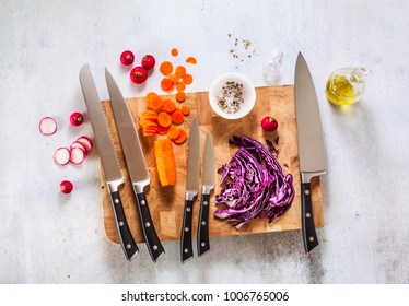 set of new professional kitchen knives on a wooden cutting board and vegetables